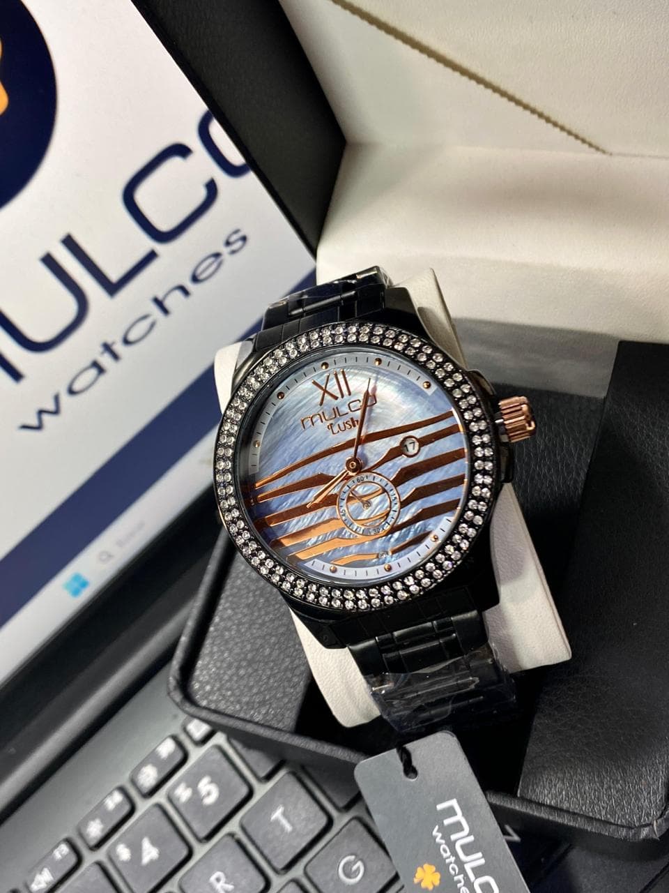 Reloj Mulco Lush negro con dial madreperla azul, rayas oro rosa y bisel pavé de cristales — relojes importados al por mayor Colombia 2026 desde $115.000 COP mayorista Kikluxe, dropshipping a Bogotá, Medellín y Barranquilla