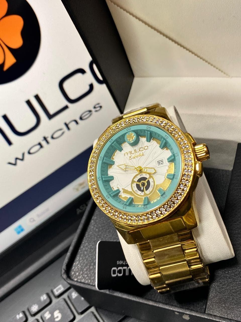 Reloj Mulco Enchanted dorado con índices turquesa menta, dial blanco tallado y bisel de doble hilera de cristales — relojes de marca al por mayor Colombia 2026 desde $115.000 COP en la bodega Kikluxe, envío 24-48h a 13 ciudades